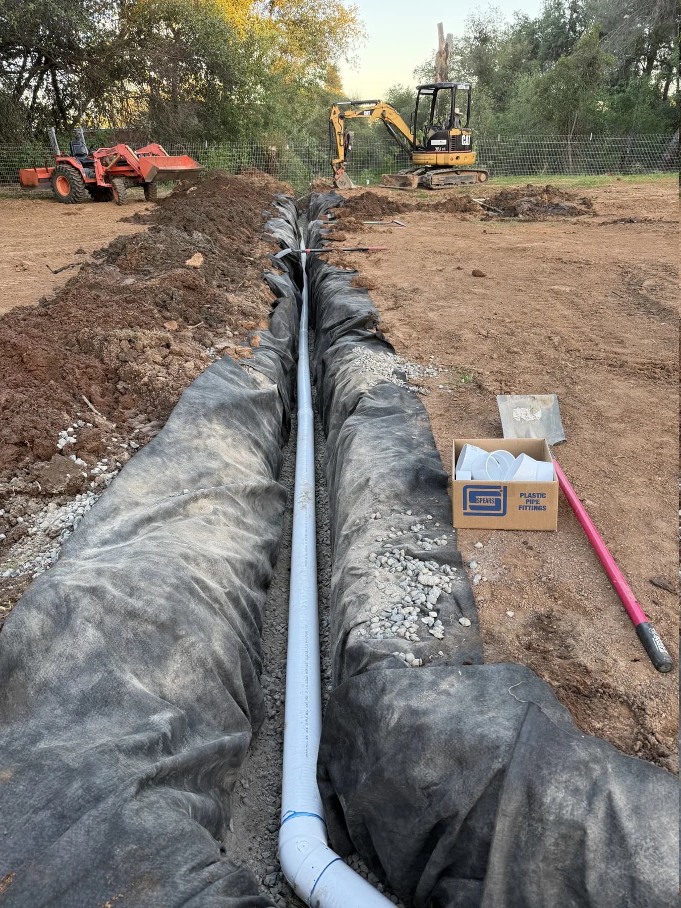 A fabric-lined drainage trench filled with gravel and pipe